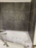 A bathtub shell in a bathroom with grey tiles