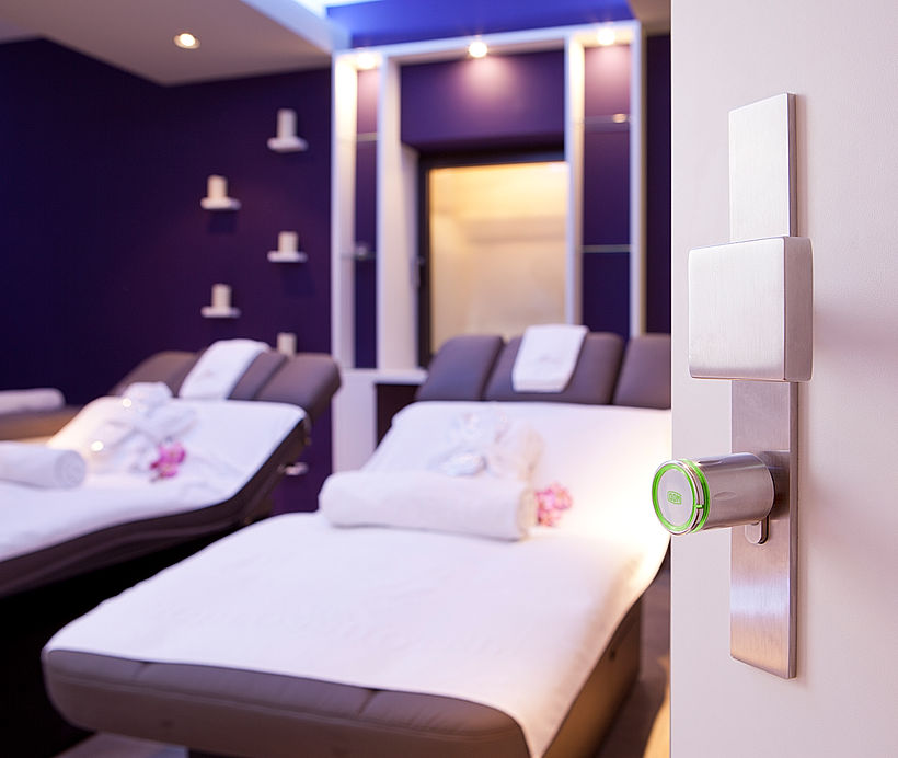 Ruheraum im Spa-Bereich eines Luxushotels mit bequemen weißen Liegen, violettem Lichtdesign und beruhigender Atmosphäre.