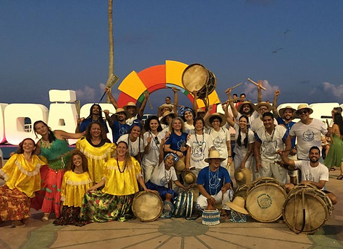 Na fotos estão reunidos batuqueiros e dançarinos após uma apresentação realizada no busto de Tamandaré, todos estão na frente do letreiro com os instrumentos
