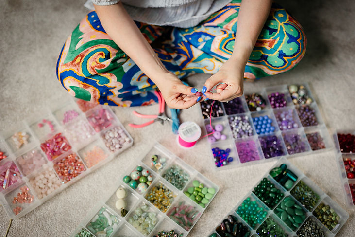 Debbie from make space making jewelry with colorful beads and pliers.