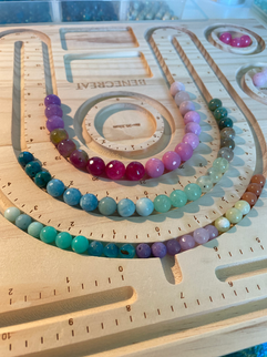 Colorful bead necklaces arranged on a wooden design board.