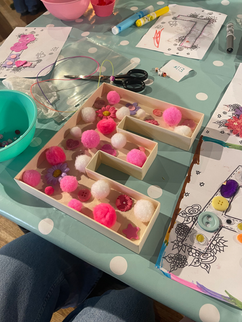 Wooden letter E filled with pink and white pom-poms.