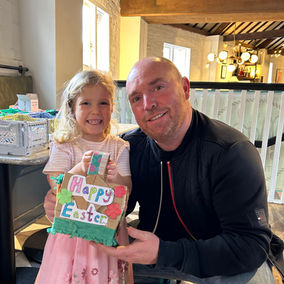 Young girl and Dad holding a Happy Easter craft which they made at a Make Space craft workshop in chelmsford