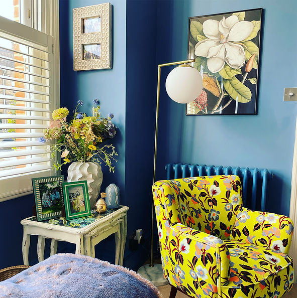 Yellow floral armchair in a blue room with a floor lamp at the Make space location home in chelmsford