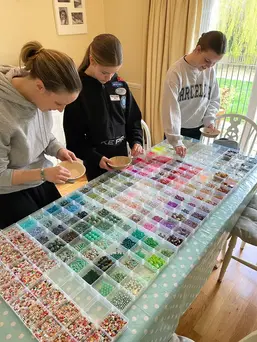 Three people organizing colorful beads at a party.
