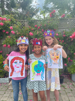 Three children in crowns holding their self-portrait art