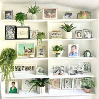 White built-in shelving with family photos and plants.
