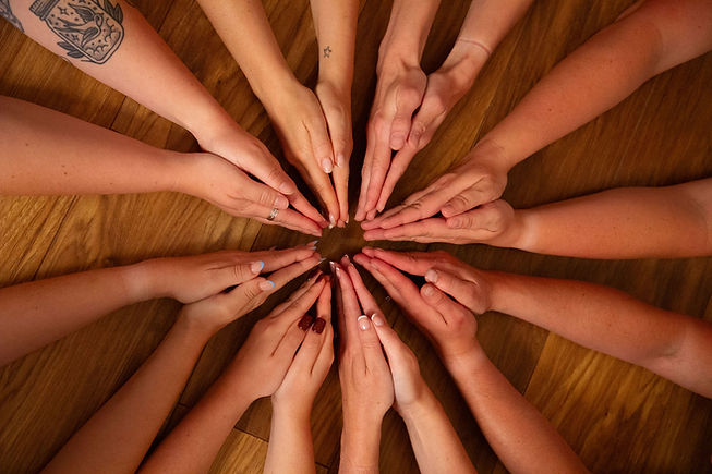 Group of hands reaching towards center to show teamwork and unity My Yogi Tribe