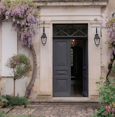Stone entrance with open dark door and purple wisteria