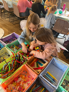 Two young girls playing with colorful craft supplies at a party.