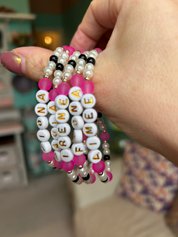 Hand holding personalized beaded name bracelets for parties