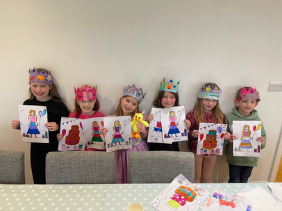 Children wearing crowns and holding their drawings at a party.