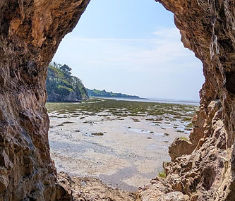 Cave opening frames a serene beach and ocean view