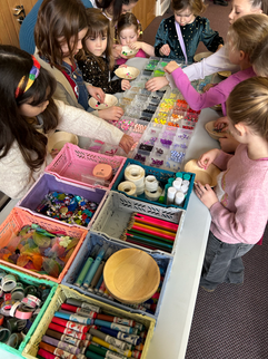 Children choosing craft supplies at a party table.