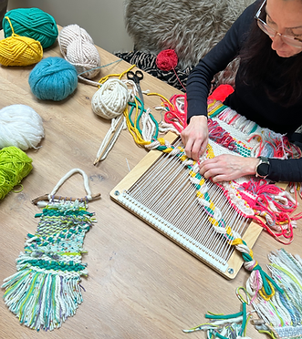 Person weaving colorful yarn on a loom during a make space craft workshop