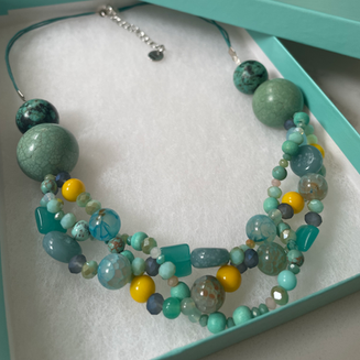 Beaded necklace with teal, green, and yellow stones in a gift box