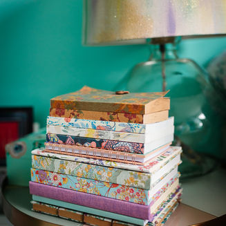 Stack of colorful books on a small table beside a lamp.