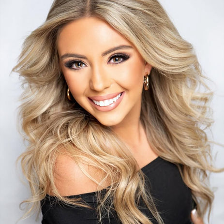 Smiling young woman with long blonde wavy hair wearing off-shoulder black top.