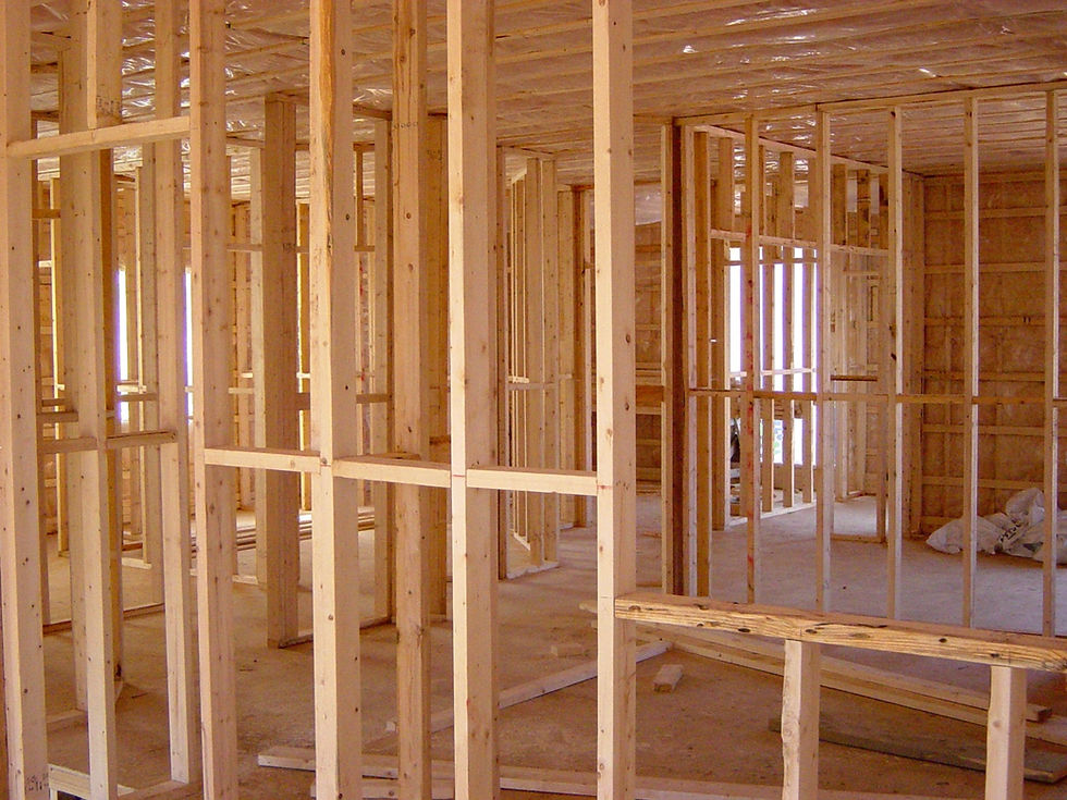 Framing stage of residential construction showcasing wooden studs and beams inside a partially built house. The image highlights the structural framework of a home under construction by Skyward Builders, emphasizing craftsmanship and quality in residential building projects. Ideal for illustrating the construction process and expertise in home building and remodeling services.