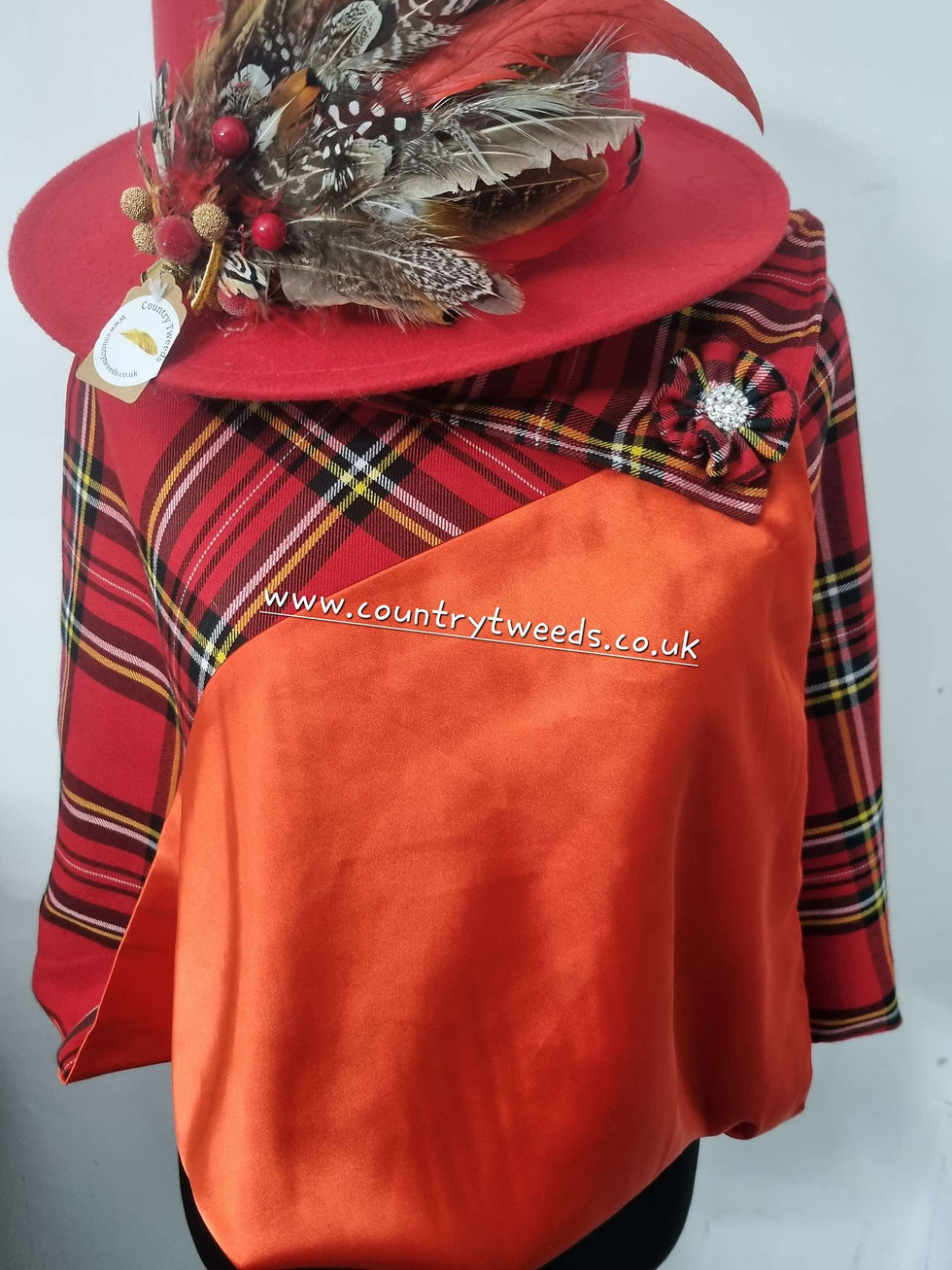 Thumbnail: Red check cape with a turned over collar and matching  detachable flower pi 