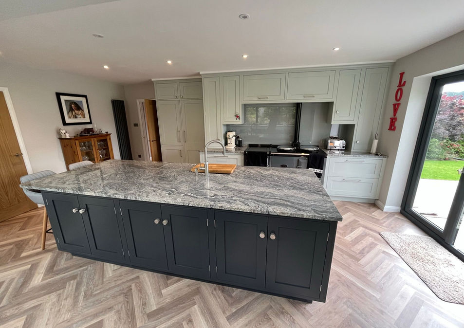 A large light kitchen with a range and a large navy kitchen island in the centre.