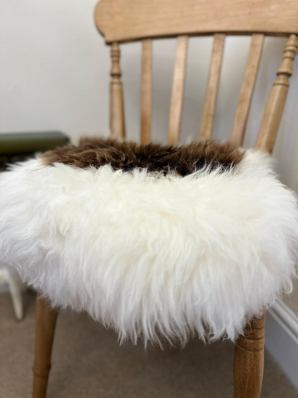 Thumbnail: Brown and White British Sheepskin Seat Pad on a wooden chair close up view