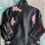 Thumbnail: Black leather jacket with pink floral embroidery. Sixteensisters.com