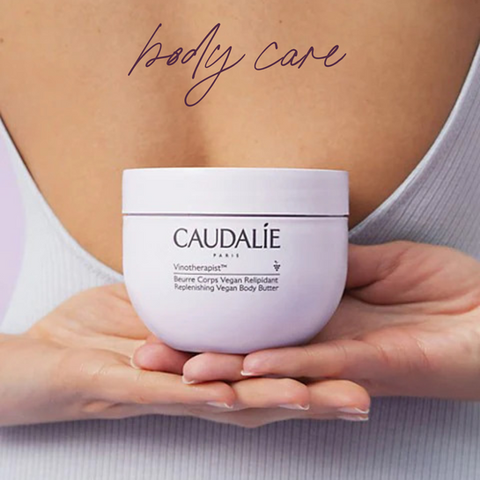 Woman holding Caudalie body butter behind her back. 