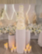 Tall white ruffle wedding cake with sugar flowers, on a pedestal at a Scarborough wedding venue
