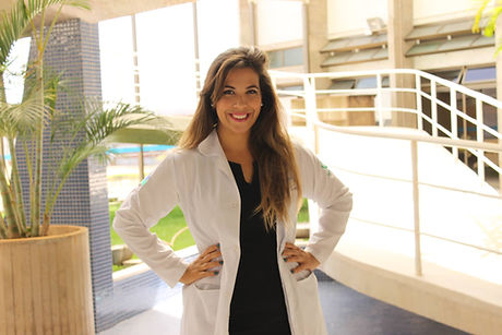 nutricionista de jaleco branco sorrindo entre uma escada e uma planta