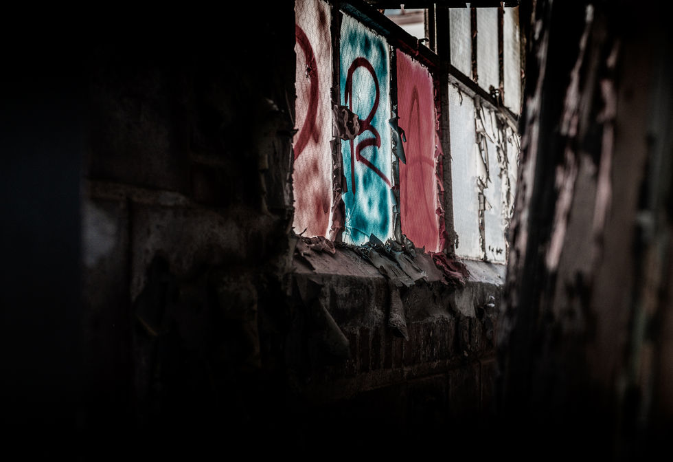 Multi-colored stained glass window of an abandoned warehouse with spray paint on the glass