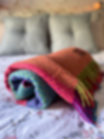 Soft merino blanket rolled up on the foot of a bed