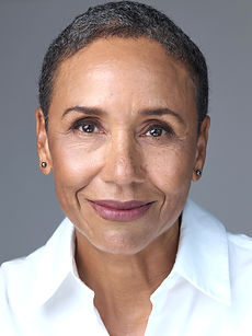 Anna R - headshot of a female actor with very short dark hair and a natural smile, wearing a white shirt, represented by Roc talent agency. 