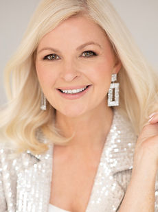 Sharon L - A headshot of a classic model with wavy hair, a natural smile and wearing a sequenced blazer represented by Roc Talent agency UK