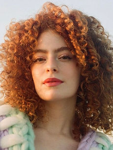 Ellie - headshot of a female model with curly hair, an intense gaze, and wearing a chunky cardigan, represented by ROC Talent Agency UK