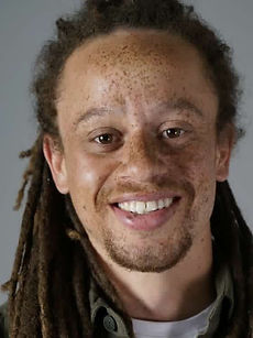 Cian - A headshot of a real model with long brown hair, light stubble, freckles, and a bright smile, represented by Roc Talent Agency UK