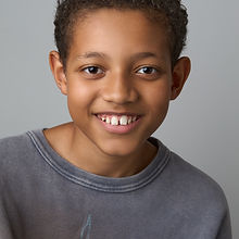 Diame - a headshot of a junior model with short hair, a wide smile, and wearing a grey shirt, represented by ROC Talent Agency UK