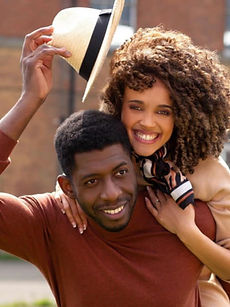 Josie and Dane - shot of a couple featuring a woman with an afro, a wide smile, she is on the man's back, he has a wide smile, and short curly hair, represented by ROC Talent Agency UK
