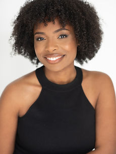 Elisha - headshot of a female actor with an afro hairstyle, wearing a high-neck black vest , and a wide smile, represented by ROC Talent Agency UK