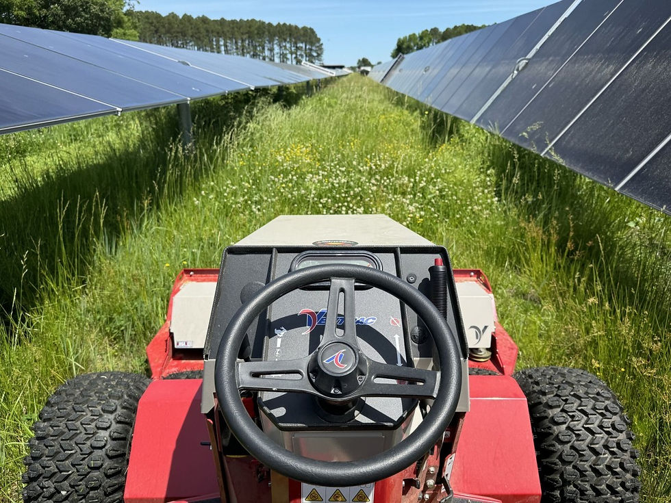 Operator view from a Ventrac compact mower navigating between solar panel rows during vegetation management on a utility-scale site