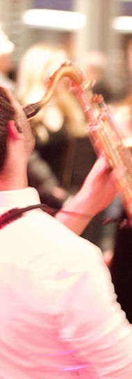 Hand Fulla Soul saxophonist leaning back while playing on the dance floor, surrounded by smiling guests enjoying the live wedding music performance.