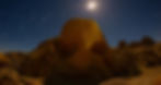 Skull Rock Joshua Tree. Large rock formations under a bright moonlit sky with star trails in the background. The scene has a tranquil, surreal atmosphere.