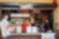 three people at a kiosk smiling and talking which selling beer