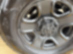 Eye-level view of a car wheel with clip-on wheel weights attached