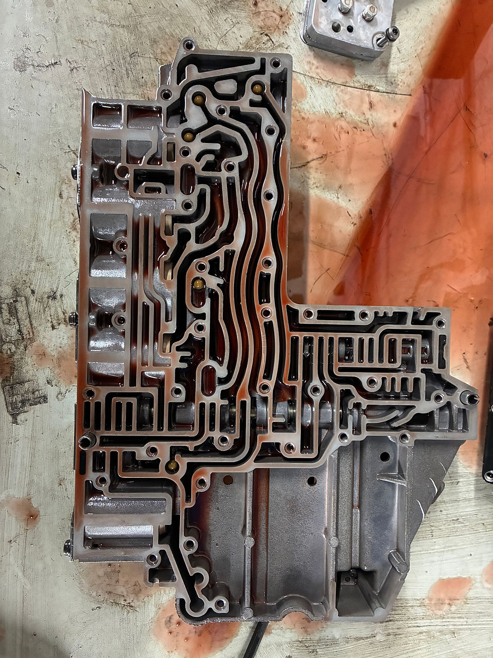 Close-up view of RFE transmission valve body showing intricate hydraulic channels