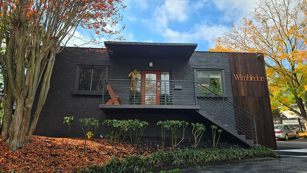 Exterior view of Wimbledon Salon Suites building, black paint, trees framing the structure.