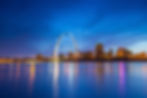 St. Louis Arch illuminated at night, city skyline reflected in water