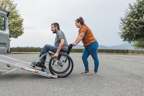 Man in wheelchair being pushed up a ramp by a woman Recon Transportation.