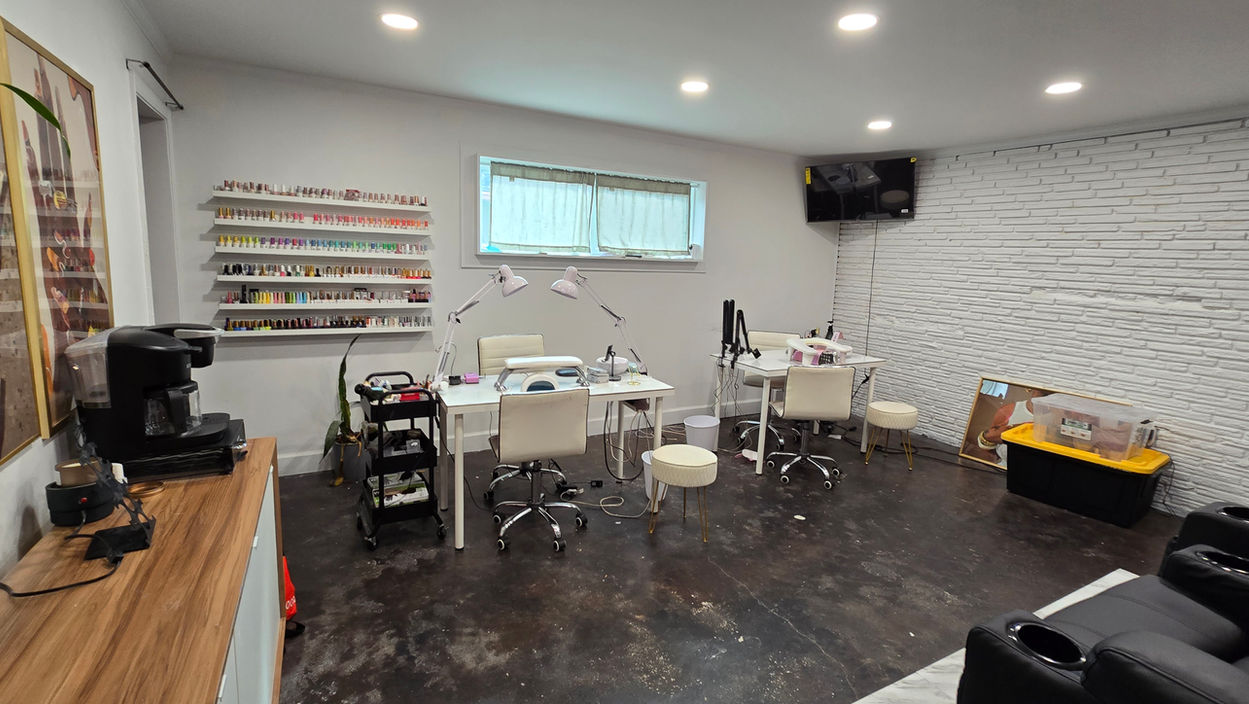 Nail salon interior with manicure tables, products, and chairs, white brick wall background WimbledonSalonSuites