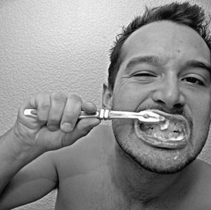 a man brushing his teeth to whiten them